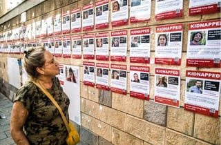 Une femme regarde un mur à Tel Aviv avec les photos des otages kidnappés par le Hamas le 7 octobre 2023. Crédit : Amir Lévy / Getty Images